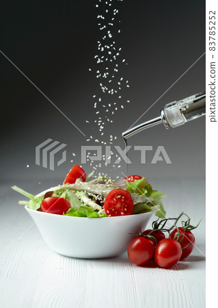 Green salad with tomatoes cherry and sesame is poured with vegetable oil. Green salad with tomatoes cherry and sesame is poured with vegetable oil. 83785252