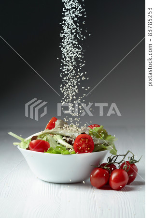 Green salad with tomatoes cherry is sprinkled with sesame seeds. Green salad with tomatoes cherry is sprinkled with sesame seeds. 83785253