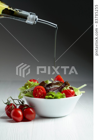 Green salad with tomatoes cherry is poured with vegetable oil. Green salad with tomatoes cherry is poured with vegetable oil. 83785255