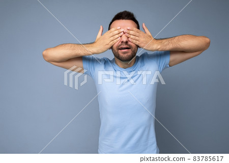 Photo of adult handsome brunet unshaven man with beard with sincere emotions wearing casual blue t Photo of adult handsome brunet unshaven man with beard with sincere emotions wearing casual blue t 83785617
