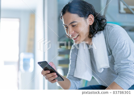 A young man taking a break with a smartphone at a construction site 83786301