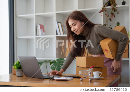 Starting Small business entrepreneur SME freelance,Portrait young woman working at home office, BOX,smartphone,laptop, online, marketing, packaging, delivery, SME, e-commerce concept. 83786410