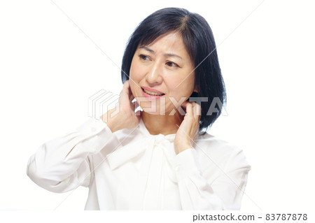 中年婦女穿著白色蝴蝶結襯衫,抓著脖子上身白色背景 中年婦女穿著白色蝴蝶結襯衫,抓著脖子上身白色背景 83787878