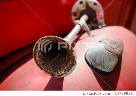 Close focus on rusty metal horn on red car. 83788938