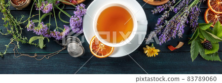 Tea panorama with copy space. Herbs, flowers and fruit around a cup of tea 83789060