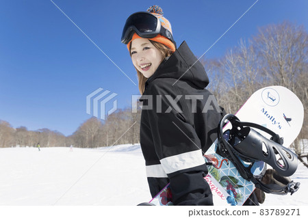 A young woman standing with a snowboard looking at the camera Snowboard image 83789271