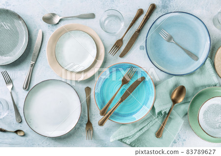 Modern tableware set with cutlery and a vibrant blue plate 83789627