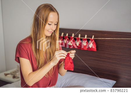 Woman making Christmas advent calendar. Pouches on a rope 83790221