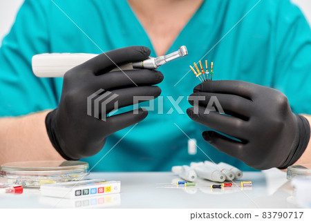 Close up of dentist hand with special tool for removing nerve from tooth. Dentist orthopedist tools. 83790717