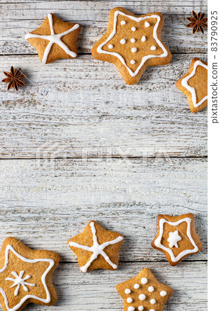Border of Christmas gingerbreads in the shape of a star with patterns of glaze and spices on a white wooden background. Border of Christmas gingerbreads in the shape of a star with patterns of glaze and spices on a white wooden background. 83790925