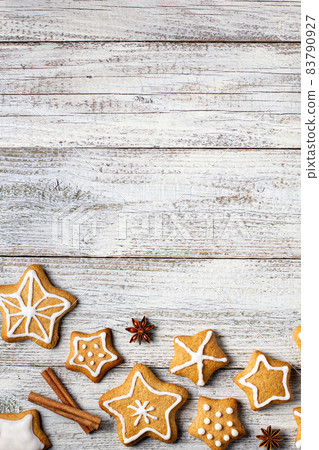 Border of Christmas gingerbreads in the shape of a star with patterns of glaze and spices on a white wooden background. Border of Christmas gingerbreads in the shape of a star with patterns of glaze and spices on a white wooden background. 83790927