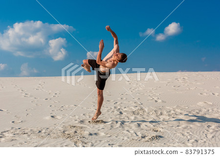 Portrait of young parkour man doing flip or somersault on the sand. Portrait of young parkour man doing flip or somersault on the sand. 83791375
