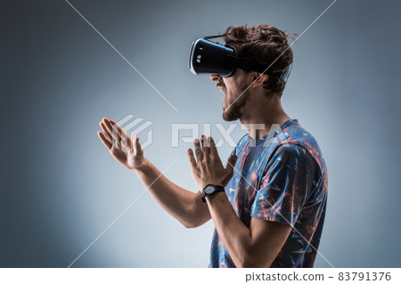 Side view of a young guy using a VR headset. Emotions Side view of a young guy using a VR headset. Emotions 83791376