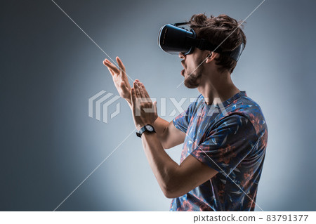 Side view of a young guy using a VR headset. Emotions Side view of a young guy using a VR headset. Emotions 83791377