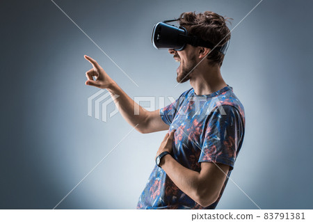 Side view of a young guy using a VR headset. Emotions Side view of a young guy using a VR headset. Emotions 83791381
