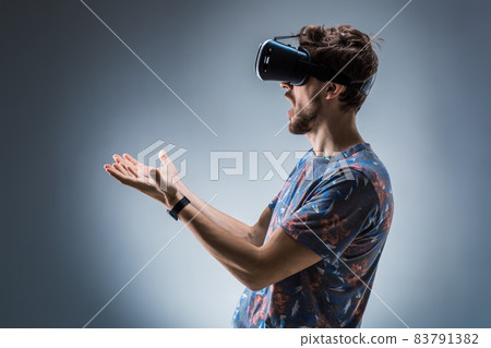 Side view of a young guy using a VR headset. Emotions Side view of a young guy using a VR headset. Emotions 83791382