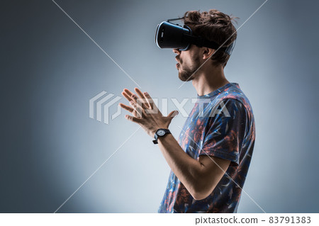 Side view of a young guy using a VR headset. Emotions Side view of a young guy using a VR headset. Emotions 83791383