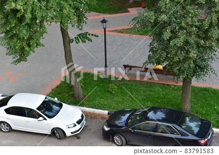 Editorial image. The city of Tambov, Russia. 08.14.2021 The picture shows two cars standing on the road near the city park. 83791583