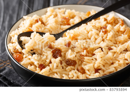 Arroz con coco is a flavorful Colombian side dish consisting of rice, coconut, sugar, salt, and raisins close-up in a bowl. horizontal 83793894