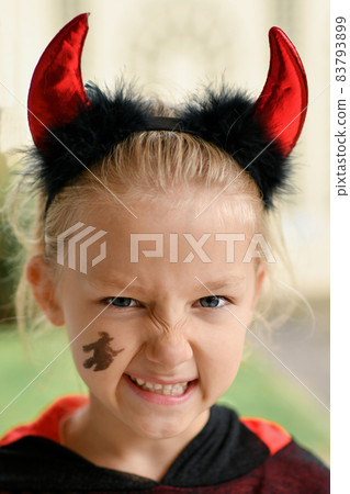 A girl dressed as a devil with horns A girl dressed as a devil with horns 83793899