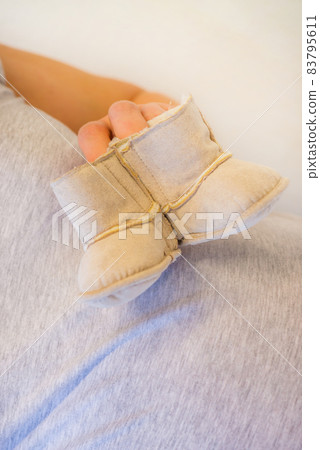 Pregnant woman holding baby booties. Macro shot Pregnant woman holding baby booties. Macro shot 83795611
