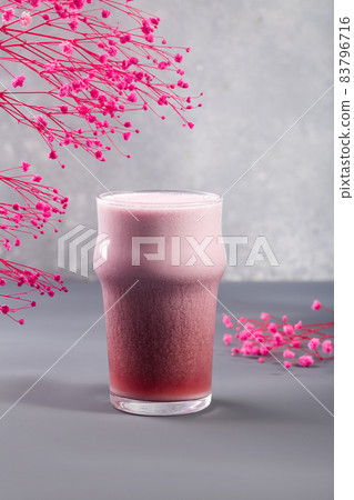 Strawberry latte on grey with flowers behind 83796716