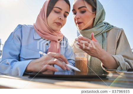 Islamic woman gesturing and giving advices to her female colleague while discussing Islamic woman gesturing and giving advices to her female colleague while discussing 83796935