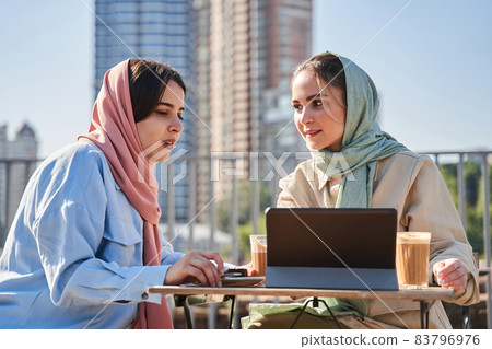 Girls wearing hijab using tablet computer and discussing something while working Girls wearing hijab using tablet computer and discussing something while working 83796976