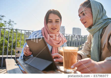 Millennial islamic women thinking about new project while working at the tablet together Millennial islamic women thinking about new project while working at the tablet together 83796977