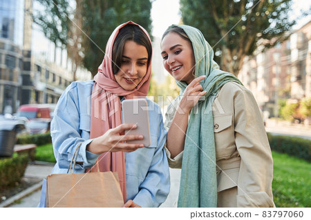 Happy islamic girls in hijab having fun and making selfie at the street during walking 83797060