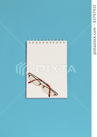 Top view of blank spiral notebook and glasses 83797432