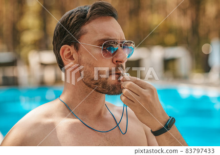 Male lifeguard in sunglasses near the public swimming pool 83797433