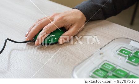 A woman with cerebral palsy uses a specialized orgonomic computer mouse. A woman with cerebral palsy uses a specialized orgonomic computer mouse. 83797516