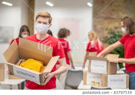 Volunteers in facial masks working with donations sorting Volunteers in facial masks working with donations sorting 83797539