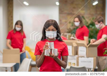 Volunteers in facial masks working with donations sorting Volunteers in facial masks working with donations sorting 83797540