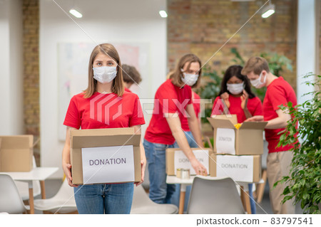 Volunteers in facial masks working with donations sorting Volunteers in facial masks working with donations sorting 83797541