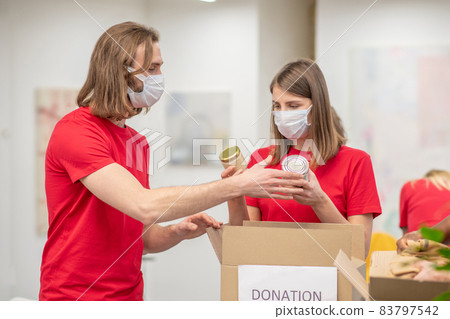 Volunteers in facial masks working with donations sorting Volunteers in facial masks working with donations sorting 83797542