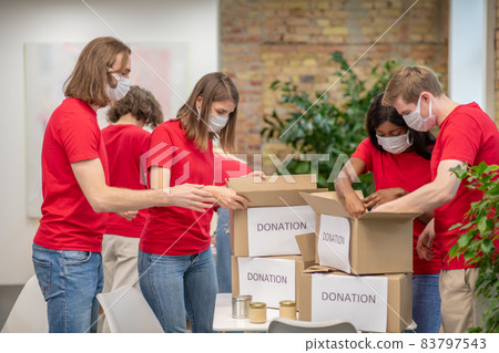 Young volunteers in red tshirts at work in a distribution point Young volunteers in red tshirts at work in a distribution point 83797543