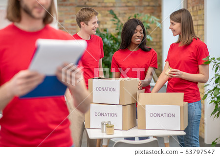Young volunteers in red tshirts at work in a distribution point Young volunteers in red tshirts at work in a distribution point 83797547