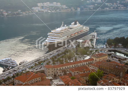 Stone houses with shingles against the background of a cruise liner. Evening in Bokokotorska Bay. The concept of tourism in Montenegro 83797929