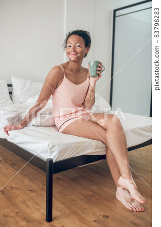 A young woman enjoyng her morning herbal tea and looking contented 83798283