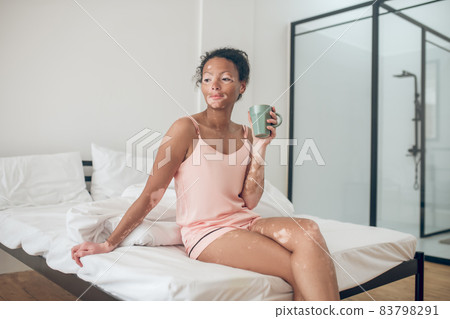 A young woman enjoying her morning herbal tea and looking contented 83798291