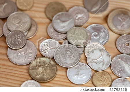 Coins laying on a wooden table surface 83798336