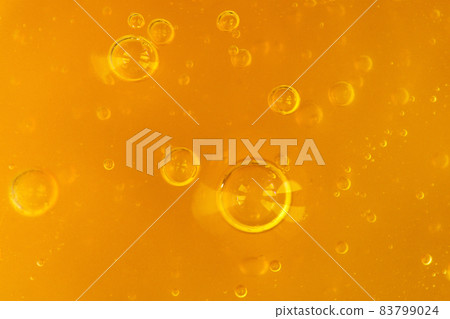 Texture of transparent yellow gel with air bubbles and waves on orange background. Concept of skin moisturizing, body care and prevention of covid19. Liquid beauty product closeup. Backdrop, flat lay 83799024