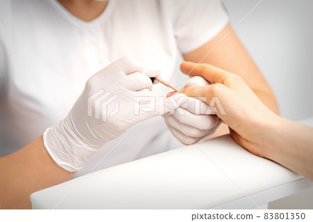 Young woman receiving pink or beige nail polish in a beauty salon. 83801350