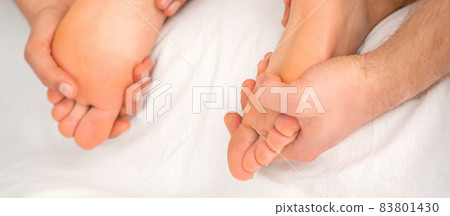 Relaxing double massage on the female feet by two masseurs in spa salon. 83801430