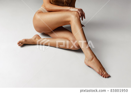 Close-up female tanned body, legs isolated over gray studio background. Natural beauty, spa, anti-cellulite concept. Close-up female tanned body, legs isolated over gray studio background. Natural beauty, spa, anti-cellulite concept. 83801950