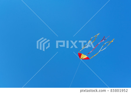 Red yellow kite fly high in blue cloudless sky. Soft focus, copy space 83801952