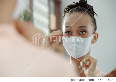 Woman Putting on White Medical Mask Woman Putting on White Medical Mask 83802398