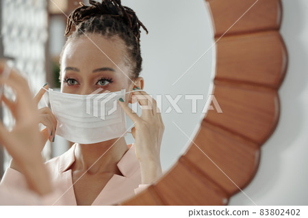 Woman Putting on Face Mask 83802402